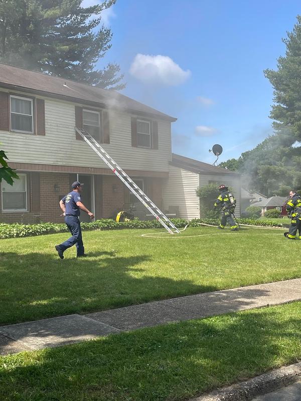 Firefighters deploying ground ladders at a dwelling fire.